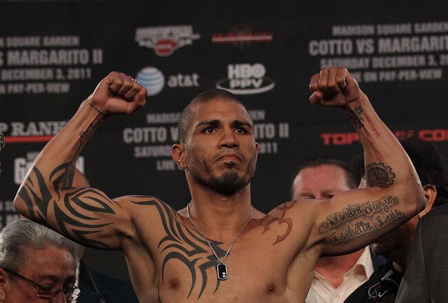 NEW YORK, NY - DECEMBER 02:  Miguel Cotto of Puerto Rico flexes his arms for the crowd on the scales ahead of his bout with Antonio Margarito of Mexico during their weigh in at The Theater at Madison Square Garden on December 2, 2011 in New York City.  (Photo by Nick Laham/Getty Images)