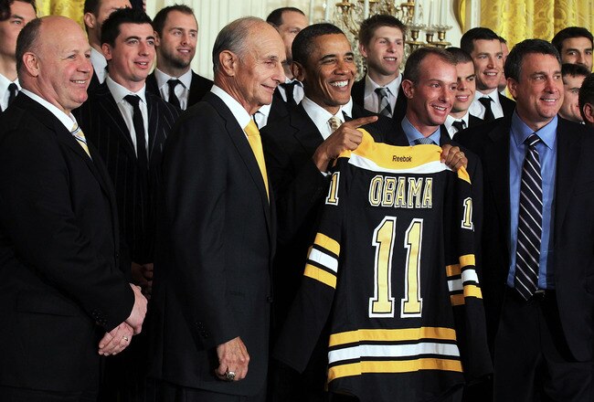 WASHINGTON, DC - JANUARY 23:  U.S. President Barack Obama (3rd L) poses for photos with members of the Boston Bruins (first row, L-R) head coach Claude Julien, team owner Jeremy Jacobs, Jacobs' son Charlie, team president of Cam Neely and assistant general manager Jim Benning after he was presented with a jersey by during a East Room event at the White House January 23, 2012 in Washington, DC. The six-time Stanley Cup champions were honored by the President for winning the 2011 Stanley Cup last June.  (Photo by Alex Wong/Getty Images)