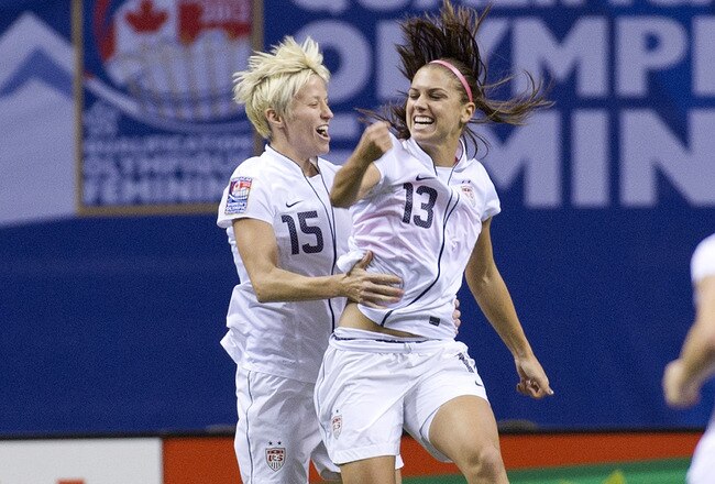 VANCOUVER, CANADA - JANUARY 29:  Alex Morgan #13 of the United States celebrates with Megan Rapinoe #15 after scoring a goal during the championship final of the 2012 CONCACAF Women's Olympic Qualifying Tournament at BC Place on January 29, 2012 in Vancouver, British Columbia, Canada.  (Photo by Rich Lam/Getty Images)