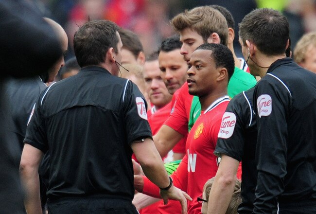 MANCHESTER, ENGLAND - FEBRUARY 11:  Patrice Evra of Manchester United talks to referee Phil Dowd after Luis Suarez of Liverpool failed to shake his hand during the Barclays Premier League match between Manchester United and Liverpool at Old Trafford on February 11, 2012 in Manchester, England.  (Photo by Shaun Botterill/Getty Images)