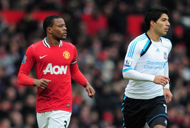 MANCHESTER, ENGLAND - FEBRUARY 11:  Patrice Evra of Manchester United jogs with Luis Suarez of Liverpool during the Barclays Premier League match between Manchester United and Liverpool at Old Trafford on February 11, 2012 in Manchester, England.  (Photo by Shaun Botterill/Getty Images)