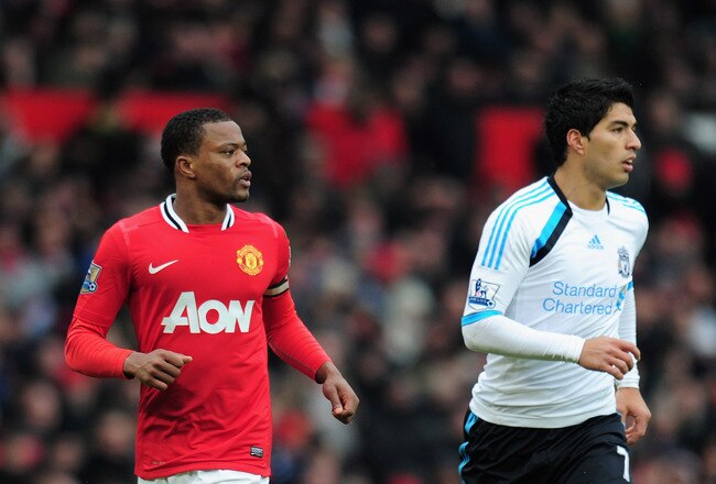 MANCHESTER, ENGLAND - FEBRUARY 11:  Patrice Evra of Manchester United jogs with Luis Suarez of Liverpool during the Barclays Premier League match between Manchester United and Liverpool at Old Trafford on February 11, 2012 in Manchester, England.  (Photo by Shaun Botterill/Getty Images)