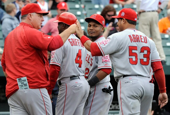 BALTIMORE, MD - SEPTEMBER 18:  Manager Mike Scioscia, left, first base coach Alfredo Griffin #4, shortstop Erick Aybar #2 and designated hitter Bobby Abreu #53 of the Los Angeles Angels of Anaheim celebrate a win after a baseball game against the Baltimore Orioles at Oriole Park at Camden Yards on September 18, 2011 in Baltimore, Maryland. The Angels beat the Orioles 11-2. (Photo by Steve Ruark/Getty Images)