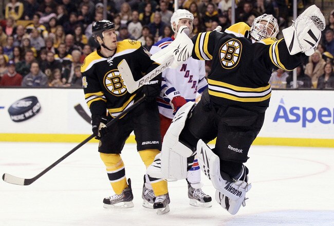 BOSTON, MA - FEBRUARY 14:  Tim Thomas #30 of the Boston Bruins leaps to catch the puck as teammate Joe Corvo #14 stands by on February 14, 2012 at TD Garden in Boston, Massachusetts.  (Photo by Elsa/Getty Images)