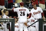 PHOENIX, AZ - OCTOBER 04:  (R) Manager Kirk Gibson greets Miguel Montero #26 of the Arizona Diamondbacks at the dugout along with other Diamondback players after Montero scores on a Paul Goldschmidt #44 single in the first inning against the Milwaukee Brewers in Game Three of the National League Division Series at Chase Field on October 4, 2011 in Phoenix, Arizona.  (Photo by Christian Petersen/Getty Images)
