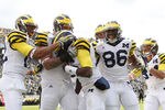 EAST LANSING, MI - OCTOBER 15: Denard Robinson #16 of the Michigan Wolverines celebrates scoring on a 15 yard run in the first quarter and is congratulated by his teammaes during the game against the Michigan State Spartans at Spartan Stadium on October 15, 2011 in East Lansing, Michigan.  (Photo by Leon Halip/Getty Images)