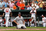 BALTIMORE, MD - MAY 23:  Kevin Youkilis #20 of the Boston Red Sox sits on the ground after being tagged out trying to score to end the third inning as pitcher Jake Arrieta #34 and catcher Luis Exposito #25 of the Baltimore Orioles walk off the fiedl at Oriole Park at Camden Yards on May 23, 2012 in Baltimore, Maryland.  (Photo by Rob Carr/Getty Images)
