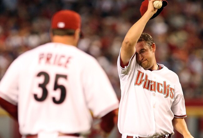 PHOENIX - APRIL 06:  Starting pitcher Brandon Webb #17 of the Arizona Diamondbacks wipes up his face as pitching coach Bryan Price #35 approaches the mound during the MLB openning day game against the Colorado Rockies at Chase Field on April 6, 2009 in Ph