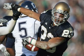 SOUTH BEND, IN - NOVEMBER 21: Golden Tate #23 of the Notre Dame Fighting Irish carries the ball as he is grabbed by Lindsay Witten #9 of the Univeristy of Connecticut Huskies at Notre Dame Stadium on November 21, 2009 in South Bend, Indiana. (Photo by Jon