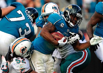 JACKSONVILLE, FL - DECEMBER 13:  Maurice Jones-Drew #32 of the Jacksonville Jaguars is tackled by Channing Crowder #52 of the Miami Dolphins during the game at Jacksonville Municipal Stadium on December 13, 2009 in Jacksonville, Florida.  The Dolphins won