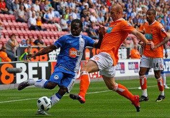 WIGAN, ENGLAND - AUGUST 14:  Victor Moses of Wigan Athletic is challenged by Stephen Crainey of Blackpool during the Barclays Premier League match between Wigan Athletic and Blackpool at the DW Stadium on August 14, 2010 in Wigan, England. (Photo by Alex 