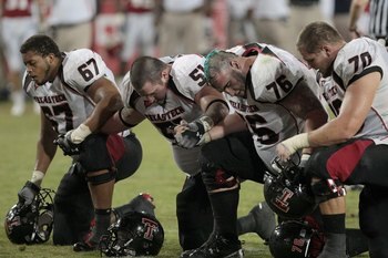HOUSTON - SEPTEMBER 26: Marlon Winn #67 , Shawn Byrnes 51, Brandon Carter 76, and Chris Olson 70 of the Texas Tech Red Raiders pray for a hurt University of Houston player at Robertson Stadium on September 26, 2009 in Houston, Texas.  (Photo by Thomas B.