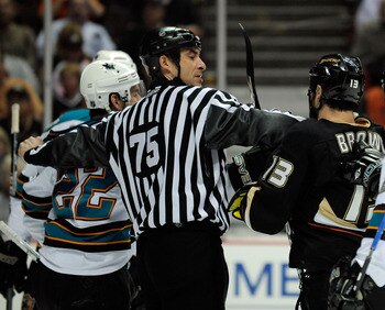ANAHEIM, CA - APRIL 23:   Linesman Derek Amell #75 separates Mike Brown #13 of the Anaheim Ducks from Dan Boyle #22 of the San Jose Sharks in the first period during Game Four of the Western Conference Quarterfinal Round of the 2009 Stanley Cup Playoffs a