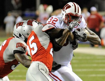 LAS VEGAS - SEPTEMBER 04:  John Clay #32 of the Wisconsin Badgers runs for yardage against Ronnie Paulo #36 and Mike Grant #25 of the UNLV Rebels during the first quarter of their game at Sam Boyd Stadium September 4, 2010 in Las Vegas, Nevada. Wisconsin