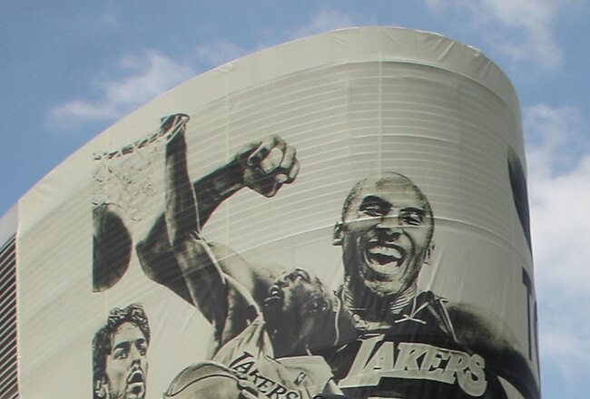 LOS ANGELES, CA - JUNE 21:  Los Angeles Lakers guard Kobe Bryant hoists the championship trophy as he rides past a mural featuring himself during the victory parade for the the NBA basketball champion team on June 21, 2010 in Los Angeles, California. The 