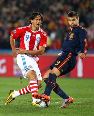 JOHANNESBURG, SOUTH AFRICA - JULY 03:  Gerard Pique of Spain tackles Roque Santa Cruz of Paraguay during the 2010 FIFA World Cup South Africa Quarter Final match between Paraguay and Spain at Ellis Park Stadium on July 3, 2010 in Johannesburg, South Afric