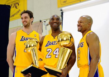 EL SEGUNDO, CA - SEPTEMBER 25:  Kobe Bryant #24  of the Los Angeles Lakers smiles as he holds two NBA Finals Larry O'Brien Championship Trophy's as he poses for a photograph with teammates Pau Gasol #16 and Derek Fisher #2 during Media Day at the Toyota C