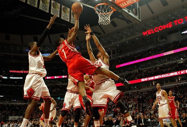 CHICAGO - MARCH 22: Kyle Lowry #7 of the Houston Rockets puts up a shot between Hakim Warrick #21 and Derrick Rose #1 of the Chicago Bulls at the United Center on March 22, 2010 in Chicago, Illinois. NOTE TO USER: User expressly acknowledges and agrees th