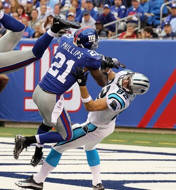 EAST RUTHERFORD, NJ - SEPTEMBER 12:  Deon Grant #34 of the New York Giants intercepts a pass in the endzone intended for Gary Barnidge #82 of the Carolina Panthers as teammate Kenny Phillips #21 defends during the first quarter on September 12, 2010 at th