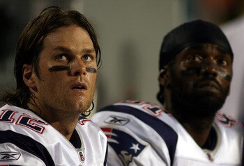 MIAMI - OCTOBER 04:  Quarterback Tom Brady #12 and Randy Moss of the New England Patriots sit on the sidelines  against the Miami Dolphins at Sun Life Stadium on October 4, 2010 in Miami, Florida.  (Photo by Marc Serota/Getty Images)