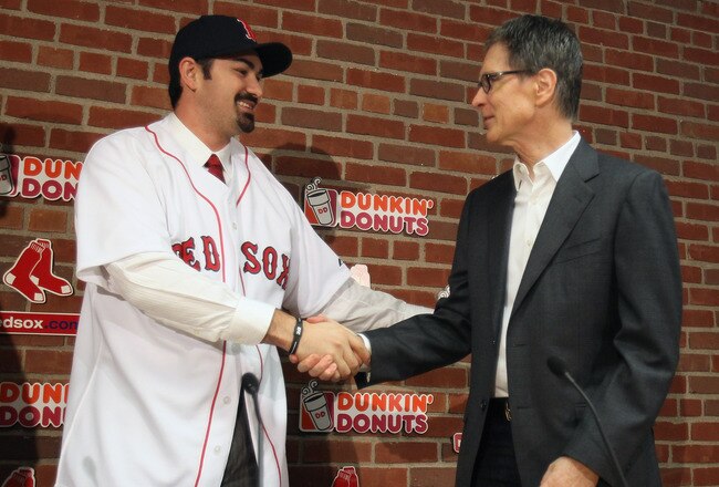 BOSTON, MA - DECEMBER 06:  Adrian Gonzalez (L) shakes hands with principle owner John Henry during a press conference announcing that he signed with the Boston Red Sox on December 6,  2010 at Fenway Park in Boston, Massachusetts.  (Photo by Elsa/Getty Ima