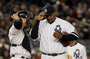 NEW YORK - OCTOBER 20:  Starting pitcher CC Sabathia #52 of the New York Yankees adjusts his cap as he talks with catcher Jorge Posada #20 after Sabathia gave up a single to Jeff Francoeur #21 of the Texas Rangers to load the bases in the top of the sixth