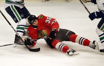 CHICAGO - DECEMBER 03: Dave Bolland #36 of the Chicago Blackhawks falls to the ice between two  Vancouver Canuck defenders at the United Center on December 3, 2010 in Chicago, Illinois. The Canucks defeated the Blackhawks 3-0. (Photo by Jonathan Daniel/Ge