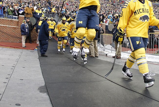 ANN ARBOR, MI - DECEMBER 11:  Lee Moffie #13 of the Michigan Wolverines jumps to the Michigan banner on his way to the ice prior to playing Michigan State at Michigan Stadium on December 11, 2010 in Ann Arbor, Michigan.  (Photo by Gregory Shamus/Getty Ima