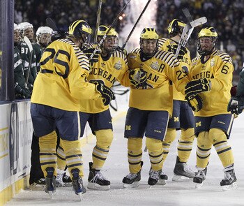 ANN ARBOR, MI - DECEMBER 11:  David Wohlberg #25 of the Michigan Wolverines celebrates a third period goal with and Lee Moffie #13, Louie Caporusso #29 and Brandon Burlon #6 while playing the Michigan State Spartans at Michigan Stadium on December 11, 201