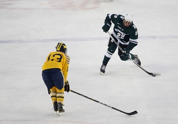 ANN ARBOR, MI - DECEMBER 11: Lee Reimer #22 of the Michigan State Spartans drives to the net as Lee Moffie #13 of the Michigan Wolverines defends during the second period of the Big Chill game at Michigan Stadium on December 11, 2010 in Ann Arbor, Michiga