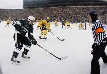 ANN ARBOR, MI - DECEMBER 11:  Mike Merrifield #13 of the Michigan State Spartans looks to get the puck around Lee Moffie #13 of the Michigan Wolverines at Michigan Stadium on December 11, 2010 in Ann Arbor, Michigan.  (Photo by Gregory Shamus/Getty Images