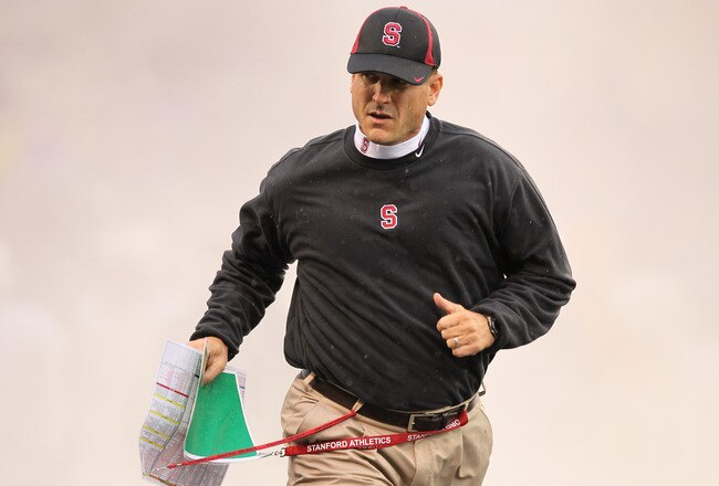 SEATTLE - OCTOBER 30:  Head coach Jim Harbaugh of the Stanford Cardinal runs through a smoke screen as he takes the field prior to the game against the Washington Huskies on October 30, 2010 at Husky Stadium in Seattle, Washington. Stanford won 41-0. (Pho