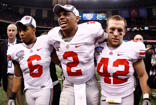 NEW ORLEANS, LA - JANUARY 04:  (M) Quarterback Terrelle Pryor #2 of the Ohio State Buckeyes is helped off the field by teammates Etienne Sabino #6 and Andrew Sweat #42 after the Buckeyes 31-26 victory against the Arkansas Razorbacks during the Allstate Su