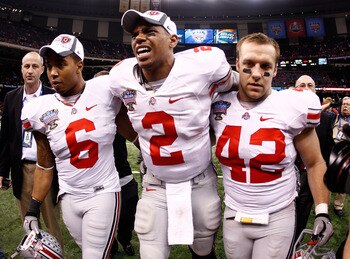NEW ORLEANS, LA - JANUARY 04:  (M) Quarterback Terrelle Pryor #2 of the Ohio State Buckeyes is helped off the field by teammates Etienne Sabino #6 and Andrew Sweat #42 after the Buckeyes 31-26 victory against the Arkansas Razorbacks during the Allstate Su