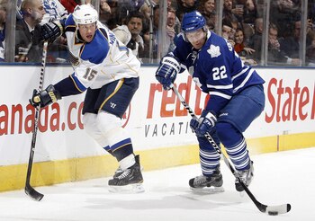 TORONTO, CANADA - JANUARY 6: Francois Beauchemin #22 of the Toronto Maple Leafs passes the puck away from Brad Winchester #15 of the St. Louis Blues during game action at the Air Canada Centre January 6, 2011 in Toronto, Ontario, Canada. (Photo by Abelima