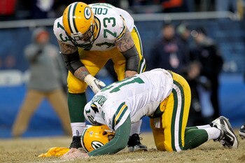 CHICAGO, IL - JANUARY 23:  Quarterback Aaron Rodgers #12 of the Green Bay Packers lays on the turf after getting hit by Julius Peppers #90 of the Chicago Bears in the helmet as Peppers was called for a personal foul in the fourth quarter of the NFC Champi