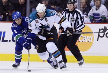VANCOUVER, CANADA - JANUARY 20: Kevin Bieksa #3 of the Vancouver Canucks gets his stick on the puck while trying to defend against Joe Thornton #19 of the San Jose Sharks during the second period in NHL action on January 20, 2011 at Rogers Arena in Vancou