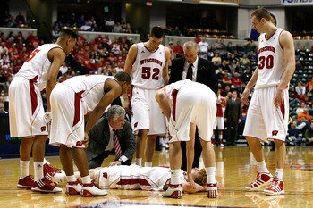 INDIANAPOLIS, IN - MARCH 11:  Mike Bruesewitz #31 of the Wisconsin Badgers is attended to by head coach Bo Ryan and the Badgers medical staff after he was hurt in the second half during the quarterfinals of the 2011 Big Ten Men's Basketball Tournament at