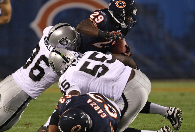 CHICAGO - AUGUST 21: Chester Taylor #29 of the Chicago Bears tries to break away from Kamerion Wimbley #96 and Rolando McClain #55 of the Oakland Raiders and past teammate Roberto Garza #63 during a preseason game at Soldier Field on August 21, 2010 in Ch