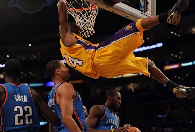 LOS ANGELES, CA - JANUARY 17:  Kobe Bryant #24 of the Los Angeles Lakers hangs on to the rim after his dunk in front of Serge Ibaka #9,Thabo Sefolosha #2 and Jeff Green #22 of the Oklahoma City Thunder at the Staples Center on January 17, 2011 in Los Ange