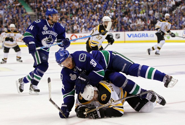 VANCOUVER, BC - JUNE 10:  Henrik Sedin #33 of the Vancouver Canucks falls over Dennis Seidenberg #44 of the Boston Bruins during Game Five of the 2011 NHL Stanley Cup Final at Rogers Arena on June 10, 2011 in Vancouver, British Columbia, Canada.  (Photo b