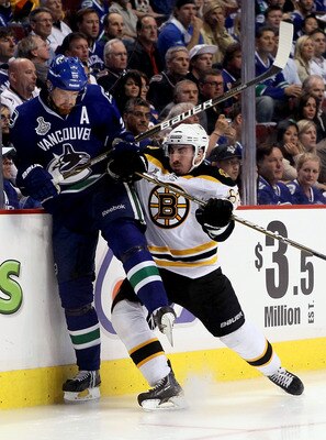 VANCOUVER, BC - JUNE 10:  Daniel Sedin #22 of the Vancouver Canucks gets checked by Brad Marchand #63 of the Boston Bruins during Game Five of the 2011 NHL Stanley Cup Final at Rogers Arena on June 10, 2011 in Vancouver, British Columbia, Canada.  (Photo