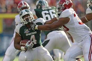 ORLANDO, FL - JANUARY 01:  Edwin Baker #4 of the Michigan State Spartans stiff arms Dont'a Hightower #30 of the Alabama Crimson Tide during the Capitol One Bowl at the Florida Citrus Bowl on January 1, 2011 in Orlando, Florida.  (Photo by Mike Ehrmann/Get