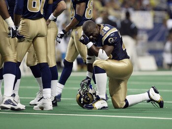 ST. LOUIS - JANUARY10:  Running back Marshall Faulk #28 of the St. Louis Rams kneels on the field with his helmet off during the NFC Divisional Playoff game against the Carolina Panthers on January 10, 2004 at the Edward Jones Dome in St. Louis, Missouri.