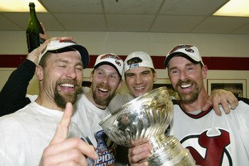 EAST RUTHERFORD, NJ - JUNE 9:  (L-R) Scott Stevens #4, Grant Marshall #29, Jamie Langenbrunner #15 and Joe Nieuwendyk #25 of the New Jersey Devils celebrate in the locker room with the Stanley Cup after defeating the Mighty Ducks of Anaheim 3-0 in game se