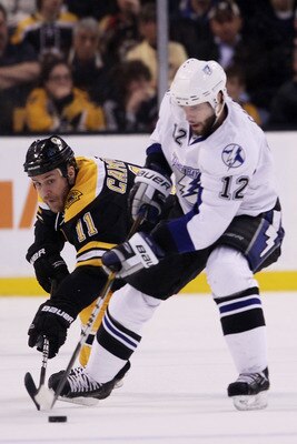 BOSTON, MA - MAY 23:  Gregory Campbell #11 of the Boston Bruins and Simon Gagne #12 of the Tampa Bay Lightning vie for the puck in Game Five of the Eastern Conference Finals during the 2011 NHL Stanley Cup Playoffs at TD Garden on May 23, 2011 in Boston,