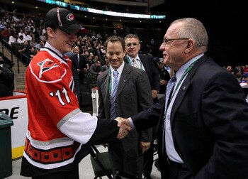 ST PAUL, MN - JUNE 25:  73rd overall pick Keegan Lowe by the Carolina Hurricanes shakes hands with General Manager Jim Rutherford as Jason Karmanos and Ron Francis look on during day two of the 2011 NHL Entry Draft at Xcel Energy Center on June 25, 2011 i