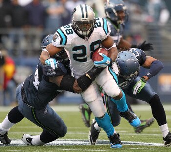 SEATTLE - DECEMBER 05:  Running back Jonathan Stewart #28 of the Carolina Panthers rushes against Junior Siavii #94 (L) and Earl Thomas #29 of the Seattle Seahawks at Qwest Field on December 5, 2010 in Seattle, Washington. The Seahawks defeated the Panthe