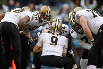 SEATTLE, WA - JANUARY 08:  Quarterback Drew Brees #9 of the New Orleans Saints kneels down in the huddle in the second quarter against the Seattle Seahawks during the 2011 NFC wild-card playoff game at Qwest Field on January 8, 2011 in Seattle, Washington