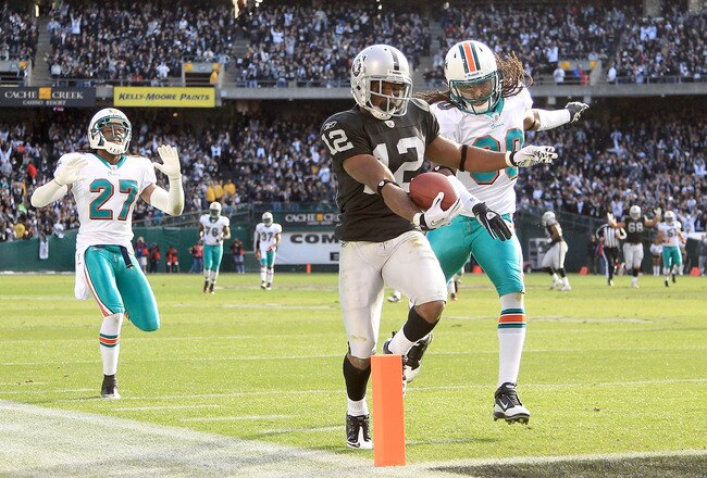 OAKLAND, CA - NOVEMBER 28:  Jacoby Ford #12 of the Oakland Raiders runs past Benny Sapp #27 and Chris Clemons #30 of the Miami Dolphins to score a touchdown at Oakland-Alameda County Coliseum on November 28, 2010 in Oakland, California.  (Photo by Ezra Sh